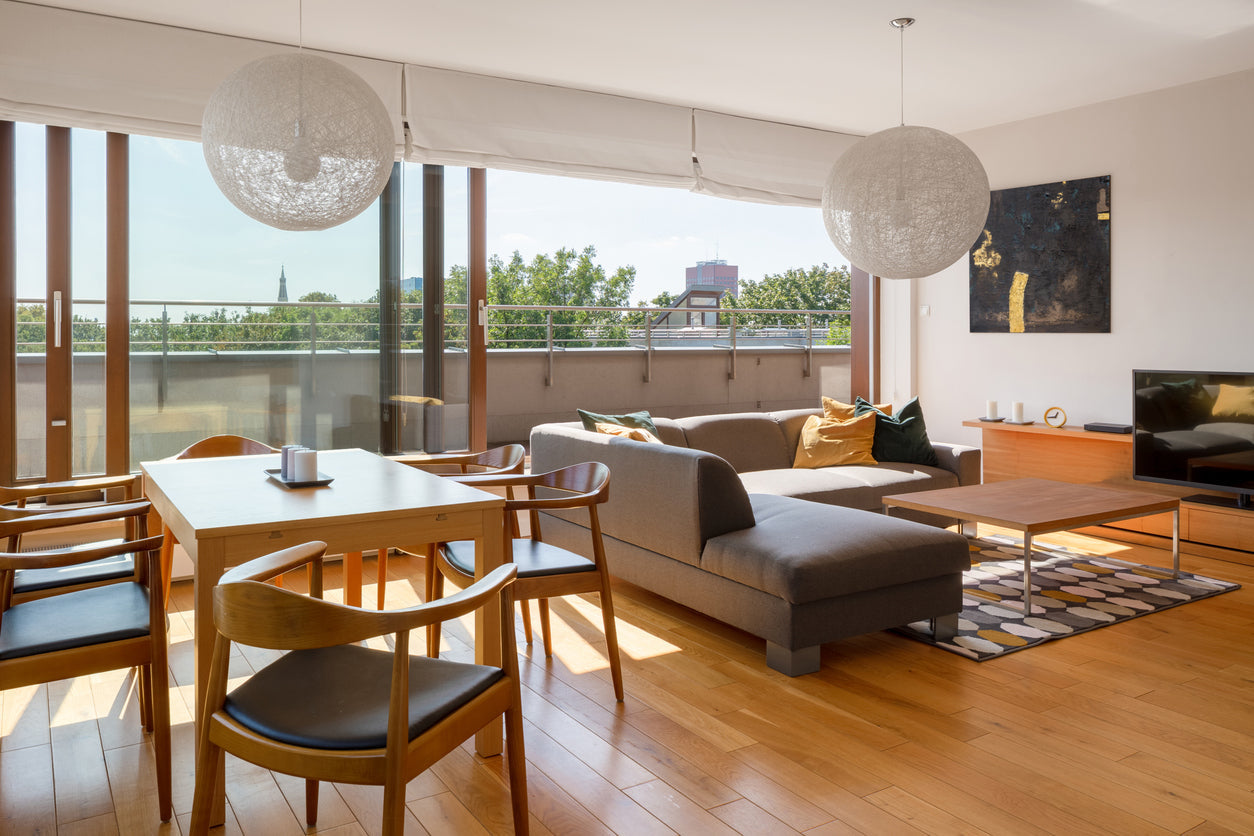 Moderne Wohnstube mit Essbereich, grossen bodentiefen Holzfenstern, stilvollem Moebel und Deckenleuchtern