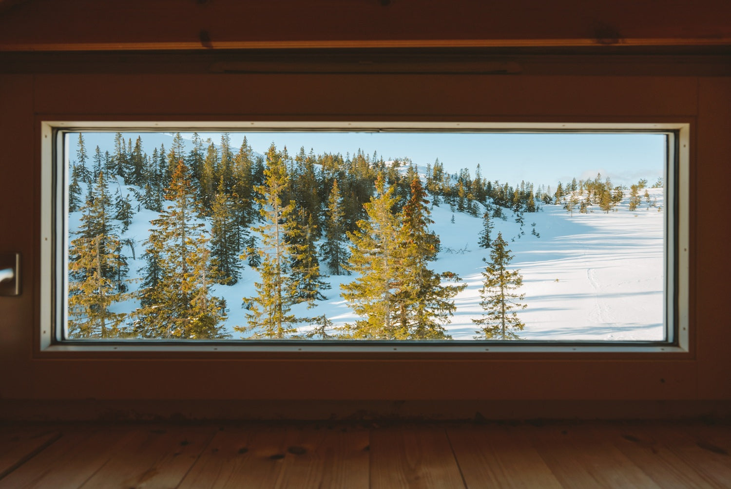 Rechteckiges Fenster von innen, Blick auf verschneite Berge, Holzfussboden, Fenster nimmt ganze Ansicht ein